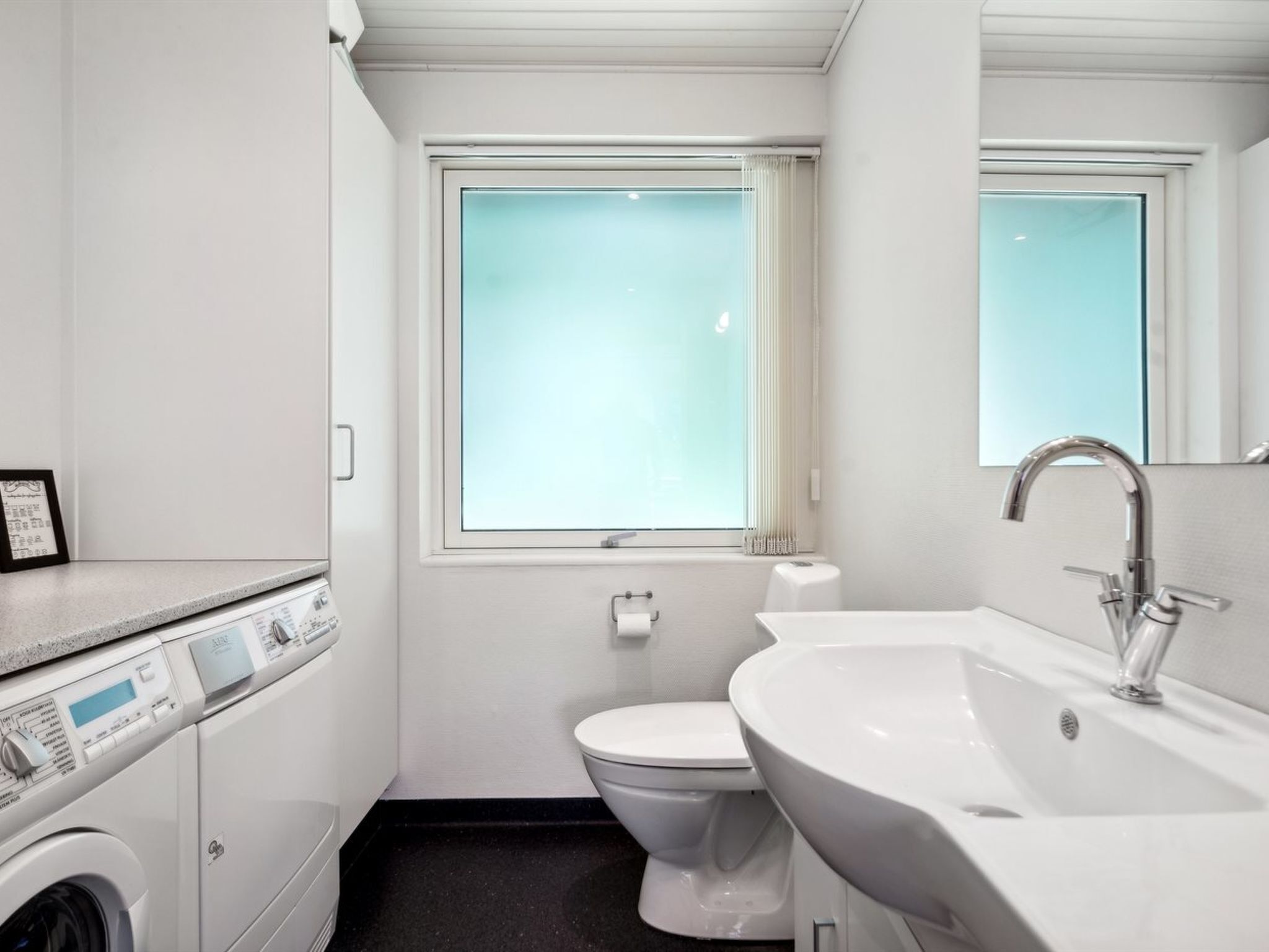 Une petite salle de bain comprenant des toilettes, un lavabo et un lave-linge.