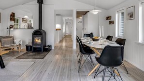 Ett modernt kök med en inbyggd spis, en matplats med ett bord för fyra personer och en mysig sittgrupp med en soffa och en bänk.
