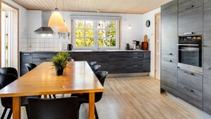 Una cocina moderna con techo de madera, un ventanal grande y horno empotrado.