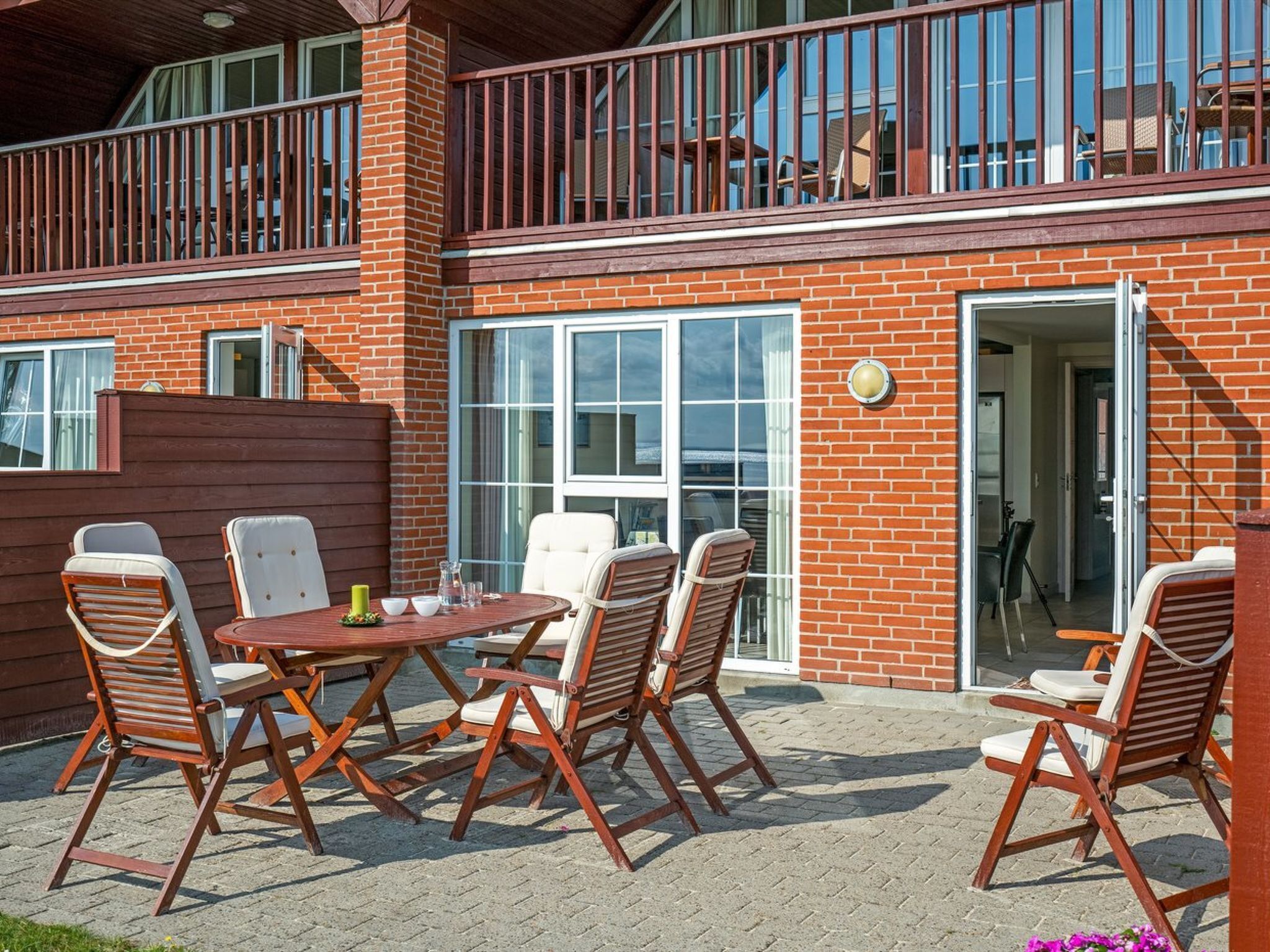 Een terras met een rijenhuis, een balkon en een tafel met stoelen.
