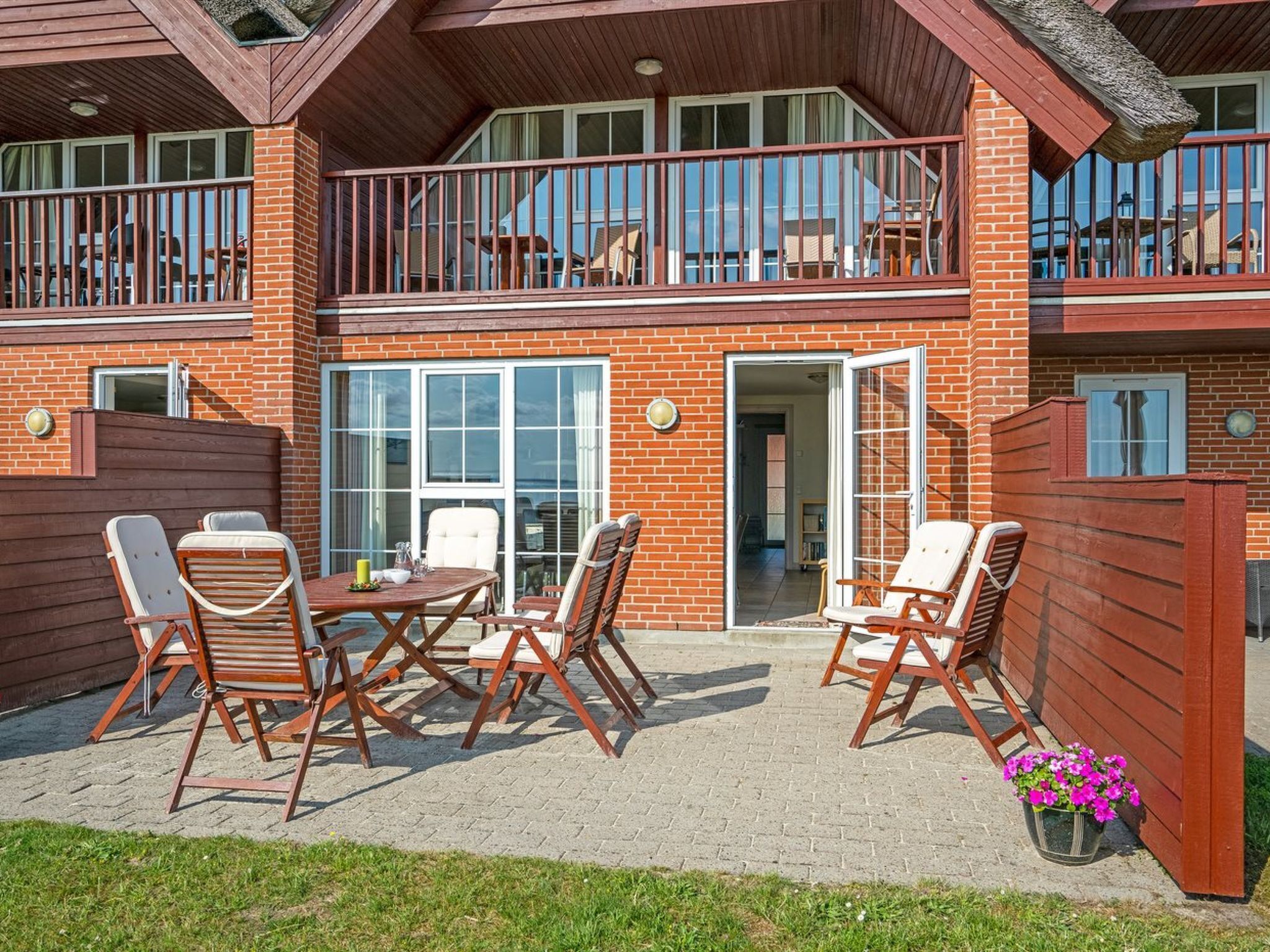 Un bâtiment à deux étages doté d’un balcon, d’une terrasse avec des meubles d’extérieur et d’une façade en briques.