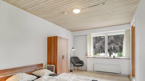 A bedroom with a bed, a wardrobe, a chair, a window, and a radiator. - "Skarthi" - 20km from the sea by Interhome (Skærbæk)