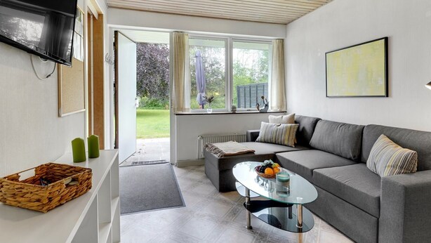 A modern living room with a grey sofa, a glass coffee table, and a TV mounted on the wall. - "Skarthi" - 20km from the sea by Interhome (Skærbæk)
