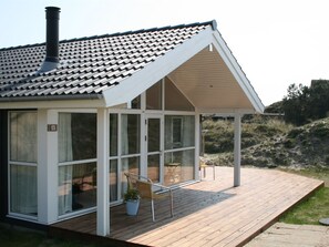 A modern house with a sloped roof, large windows, and a wooden deck.