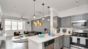 Cozinha moderna com armários cinza, eletrodomésticos de aço inoxidável e iluminação pendente.