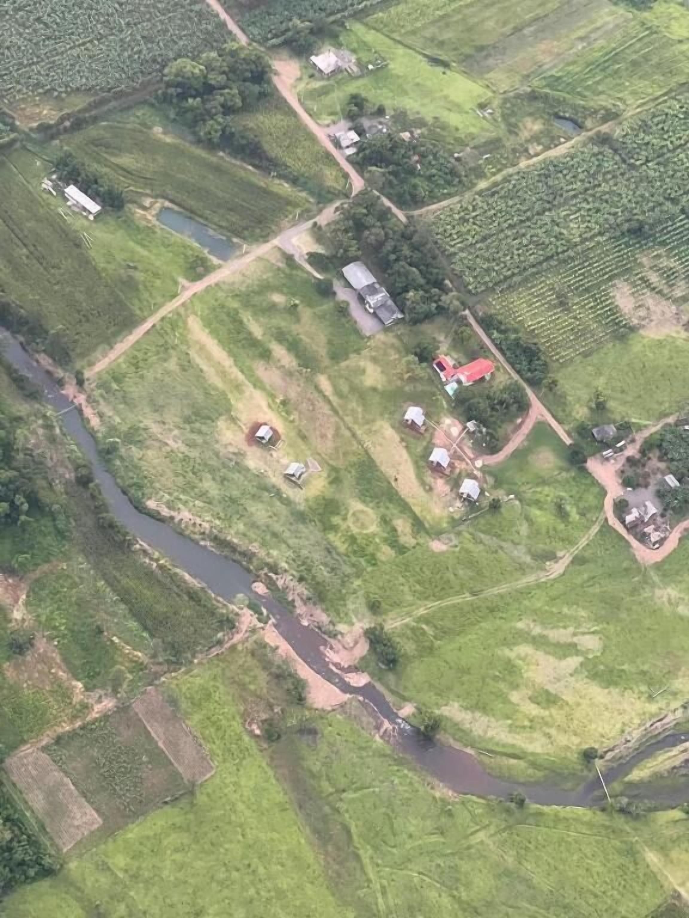 An aerial view of a rural area with fields, a river, and scattered houses.