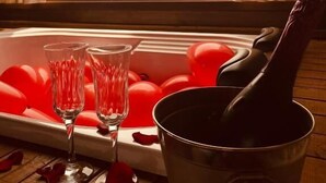 Una vasca da bagno con champagne, bicchieri e petali di rosa.