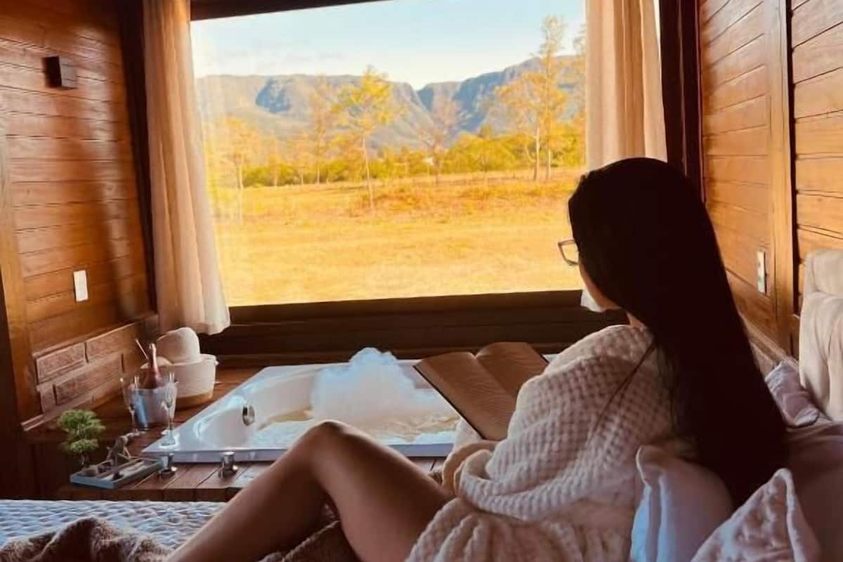 A cozy cabin interior with a large window offering a view of a mountainous landscape.