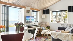 A modern living room with a large TV, a dining area, and a cozy seating area with a view of the sea. - "Tameka" - 10m to the fjord by Interhome (Munkebo)