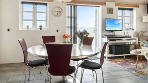 A dining area with a round table, four chairs, a chandelier, and a view of the sea through large windows. - "Tameka" - 10m to the fjord by Interhome (Munkebo)