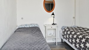 A bedroom with two single beds, a bedside table with a lamp, a small white cabinet, and a round mirror on the wall. - "Tameka" - 10m to the fjord by Interhome (Munkebo)