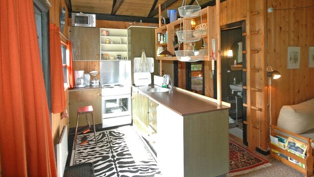A compact kitchen with wooden walls, a central island, and a zebra-patterned rug. - "Spasena" - 400m from the sea by Interhome (Gedser)
