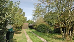 A garden pathway leading to a wooden shed, surrounded by lush greenery and trees. - "Spasena" - 400m from the sea by Interhome (Gedser)