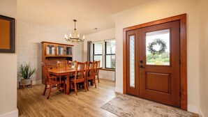 A dining area with a wooden table and chairs, a chandelier, and a potted plant. - Cozy Retreat Family Home (Klamath Falls, OR)