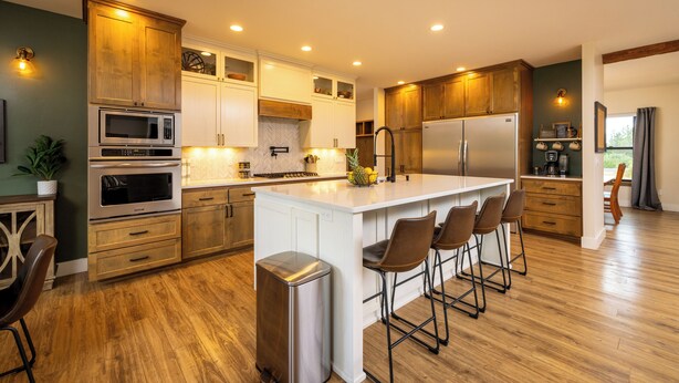 A modern kitchen with wooden cabinets, stainless steel appliances, and a central island with bar stools. - Cozy Retreat Family Home (Klamath Falls, OR)