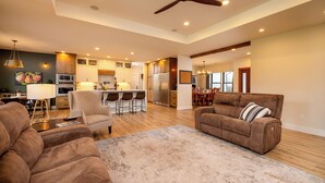 A spacious living room with a large brown sofa, a coffee table, and a dining area with a wooden table and chairs. - Cozy Retreat Family Home (Klamath Falls, OR)