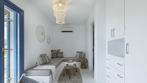 Una habitación moderna y minimalista con una zona de estar con bancos integrados, una pequeña mesa redonda y un armario blanco.