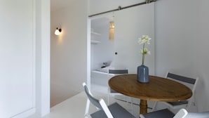 Un coin repas avec une table ronde en bois, des chaises blanches et un vase rempli de fleurs.