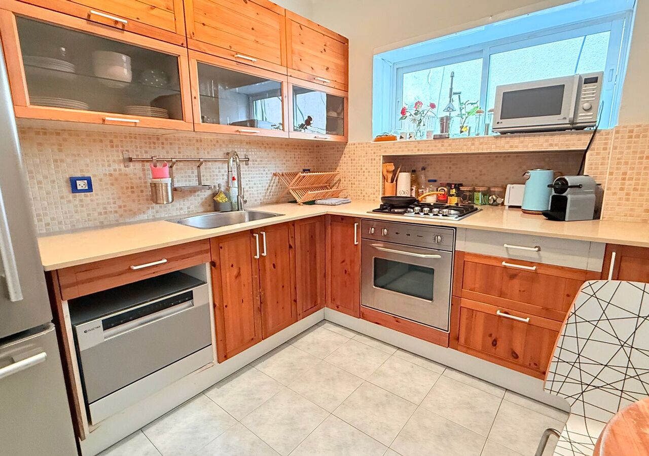 A kitchen with wooden cabinets, a stainless steel oven, a microwave, and a window with a view of the outdoors.