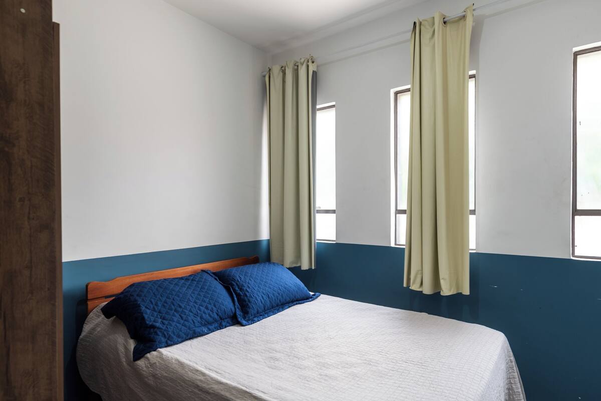 Una camera da letto con un letto, tende e finestre.