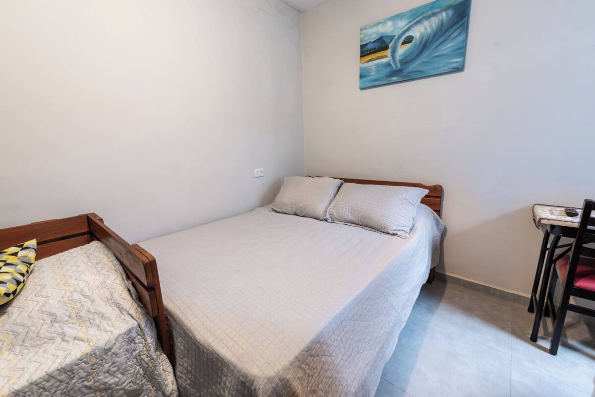 Una camera da letto piccola e ordinata con un letto singolo, una sedia e un quadro appeso al muro.