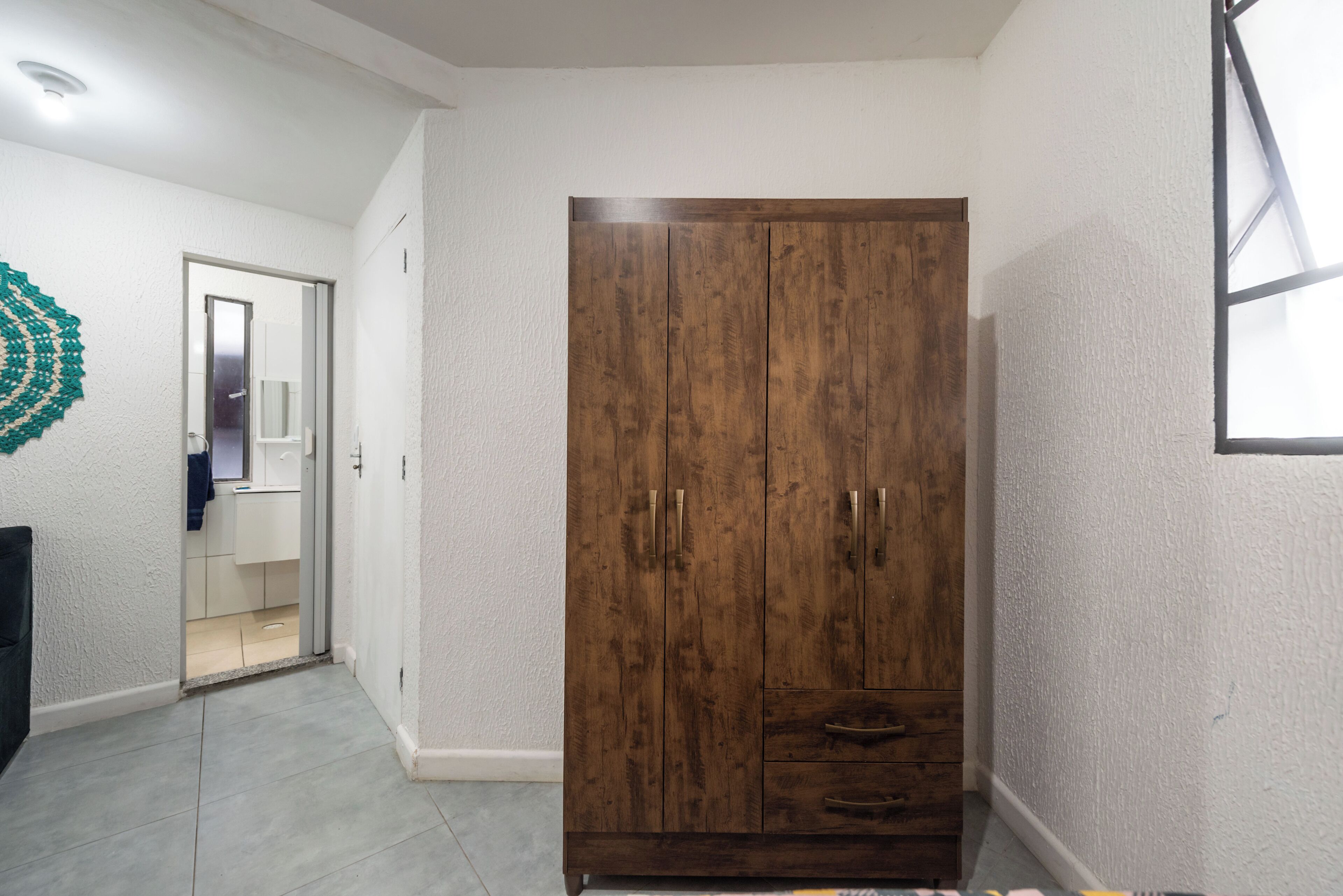 A hallway with a wooden wardrobe, a door leading to a bathroom, and a textured wall.
