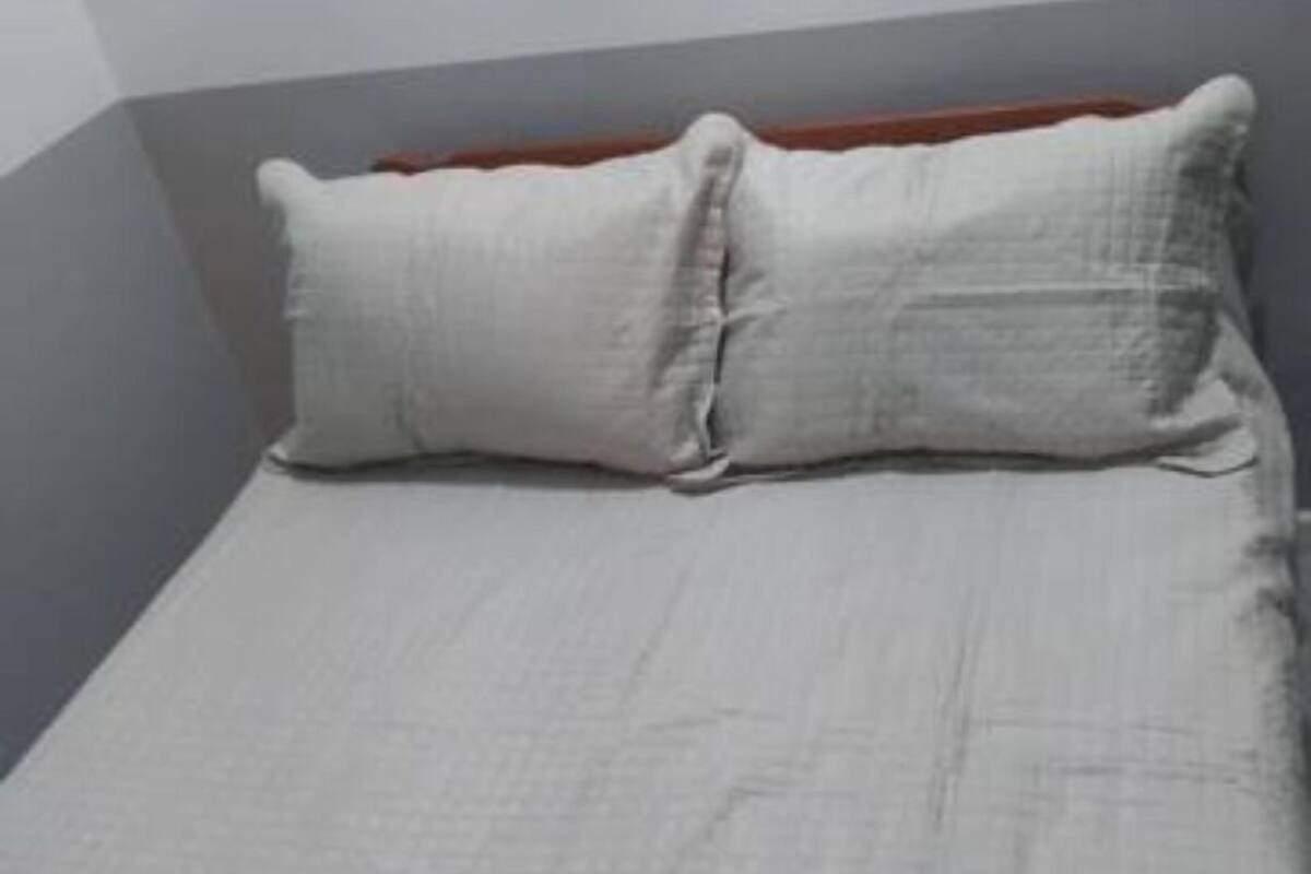 Un letto con una coperta trapuntata grigia e due cuscini.