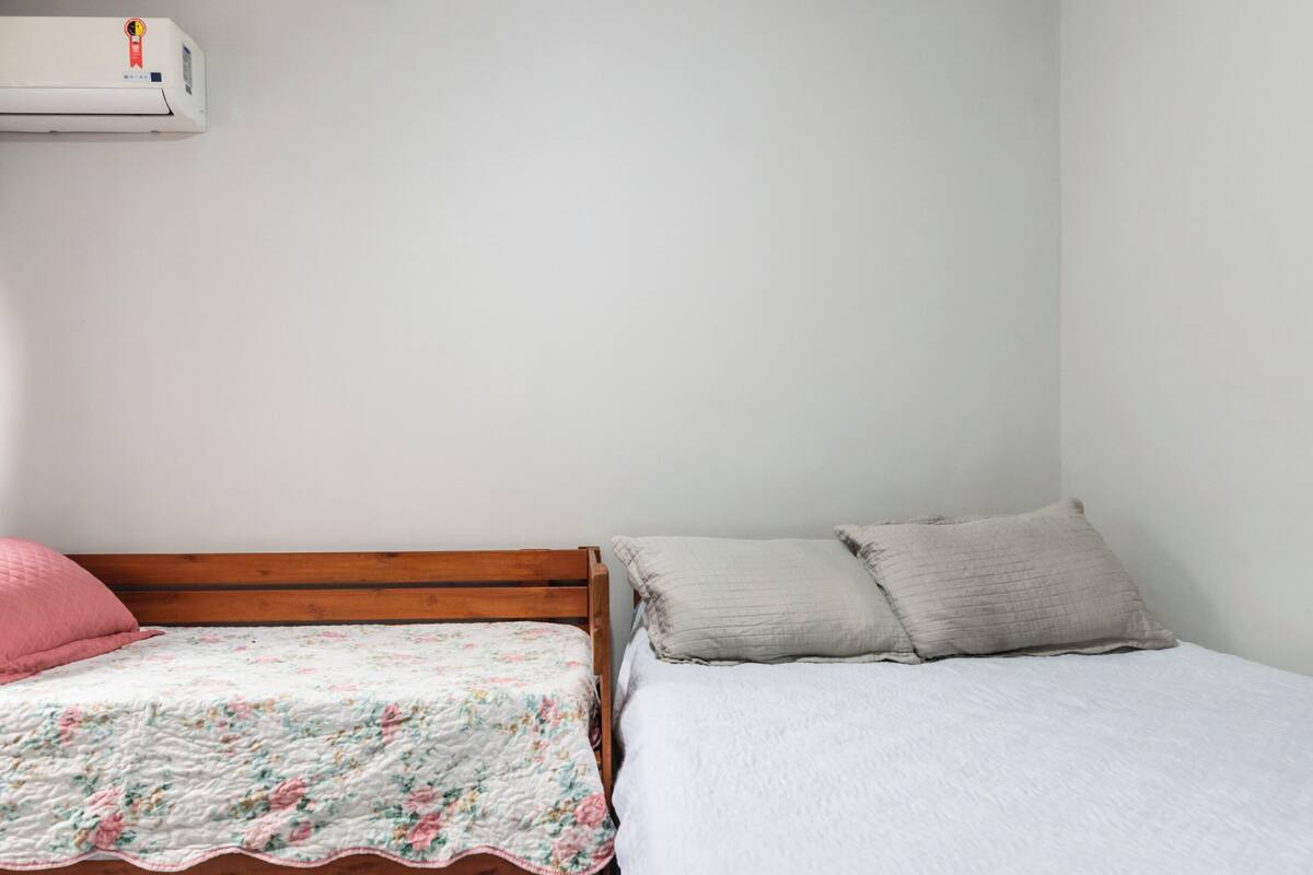 Una camera da letto con due letti, uno con copripiumino floreale e l’altro con copripiumino bianco.