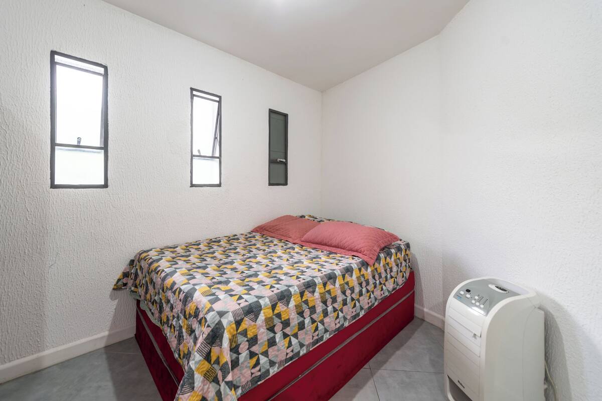 Una camera da letto con un letto, una finestra, una porta e un termosifone.
