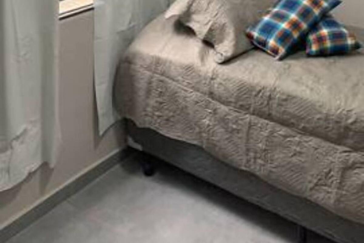 Una camera da letto con un letto, una finestra con tende bianche e un tavolino.