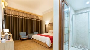 A hotel room with a bed, a desk with a lamp, a chair, a shower, and a curtain. - Haolong Hotel (Qionghai Yinhai Road Grain Street Branch) (Qionghai)