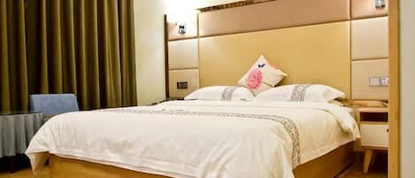 Une chambre d’hôtel avec un grand lit, une table de chevet, une commode et une fenêtre avec des rideaux.