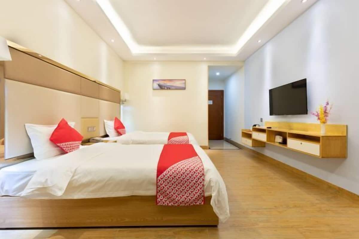 A hotel room with a large bed, a TV, a wooden console table, and a painting on the wall.