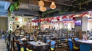 A restaurant with multiple tables and chairs, a bar area, and a counter with a television screen. - Haolong Hotel (Qionghai Yinhai Road Grain Street Branch) (Qionghai)