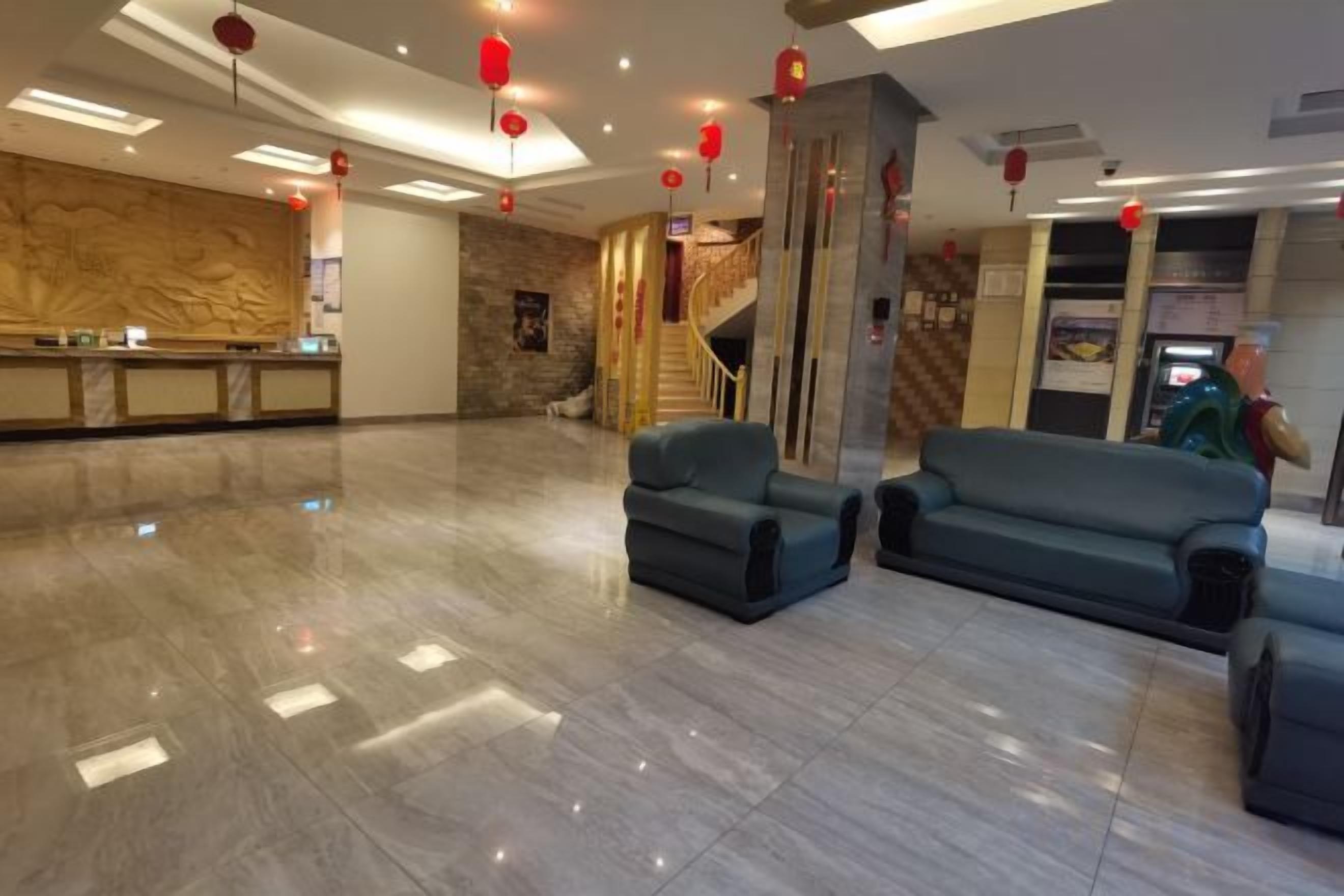 Un vestíbulo de hotel con recepción, zona de estar y una escalera.