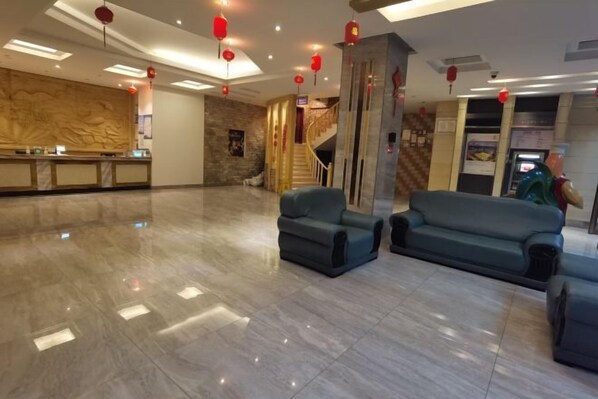 Eine geräumige Lobby mit Marmorboden, einer Rezeption und einer Treppe zu den oberen Etagen.