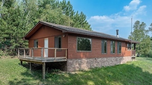A wooden cabin with a balcony, surrounded by trees.