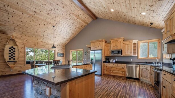 A spacious kitchen with wooden cabinets, a central island, and a stone accent wall.