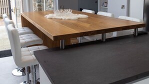 A modern dining area with a wooden table, white chairs, and a black pendant light. - Luxury Home on Valentia Island, Nightstown with sea view, Electric Car Charger (Valentia Island)