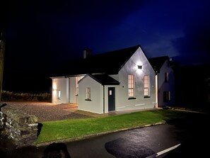 A two-story house with a dark roof, a front door, and two windows on the ground floor.