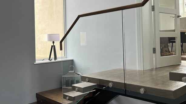 A modern staircase with glass railings and wooden steps leading to a second floor. - Luxury Home on Valentia Island, Nightstown with sea view, Electric Car Charger (Valentia Island)