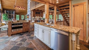 A spacious kitchen with granite countertops, stainless steel appliances, and a large island. - The Hideaway on Little Jay | Log Home | (Cohasset)