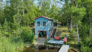 A blue cabin with a dock and a small staircase leading up to it, surrounded by dense forest. - Dog Friendly, Cozy, Private, Convenient | Long Lake Lookout (Cohasset)