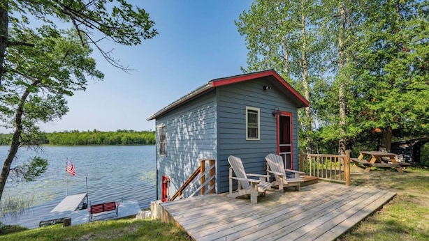 A small cabin with a dock, two Adirondack chairs, and a picnic table on a wooden deck. - Dog Friendly, Cozy, Private, Convenient | Long Lake Lookout (Cohasset)