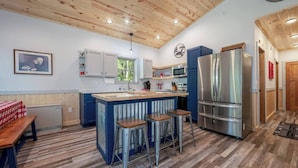 A kitchen with a central island, bar stools, a double-door refrigerator, and a microwave. - Dog Friendly, Cozy, Private, Convenient | Long Lake Lookout (Cohasset)