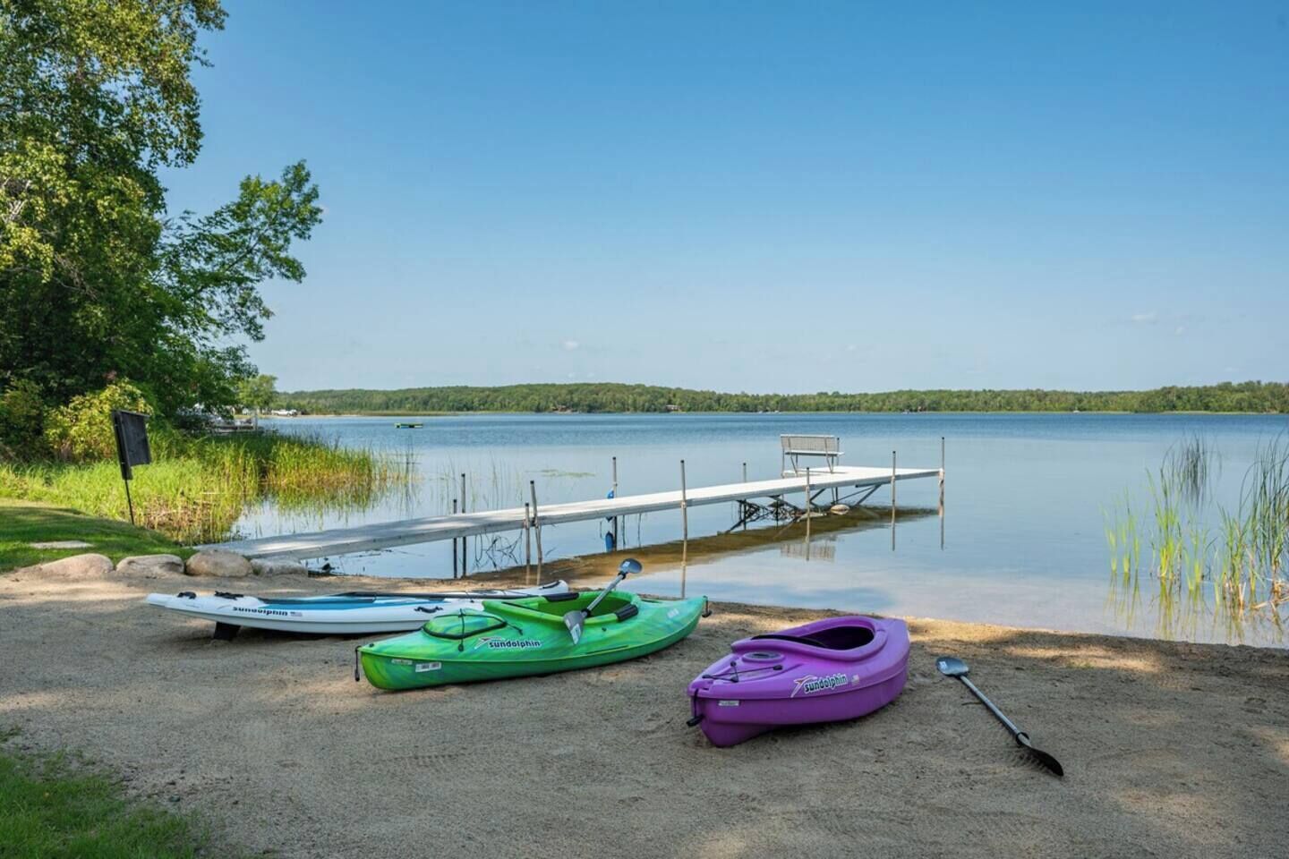 Un'incantevole vista sul lago con un pontile, kayak e un remo.