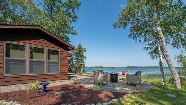 A cabin with a patio area featuring outdoor furniture and a stone fire pit.