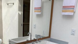 Un baño moderno con dos lavamanos, un espejo grande y un banco de madera.