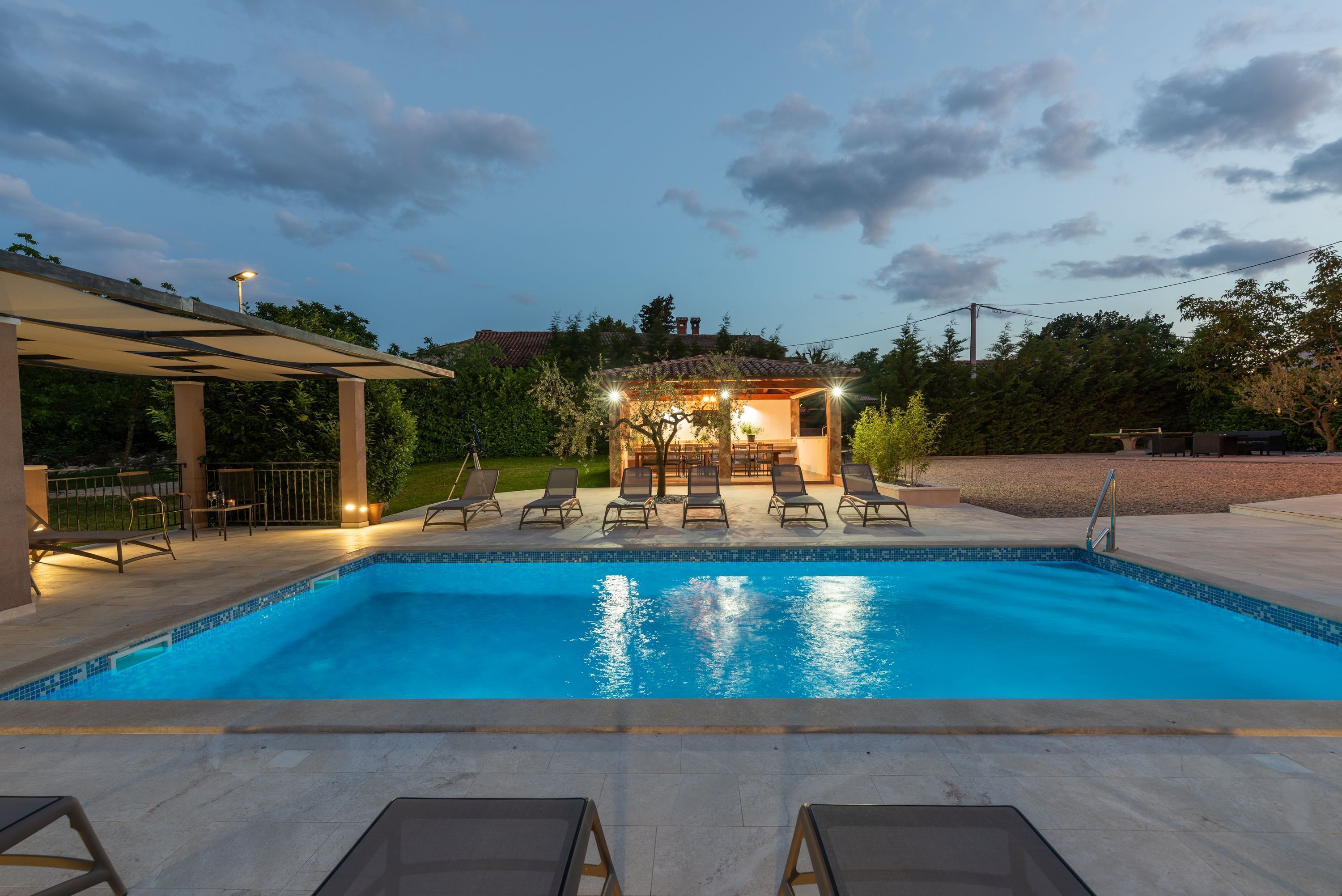 A swimming pool with lounge chairs and a covered seating area.