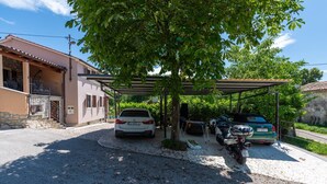 A residential area with a covered parking area, a white car, and a motorcycle parked under a tree. - Vesna Branka in Pi an (Pican)